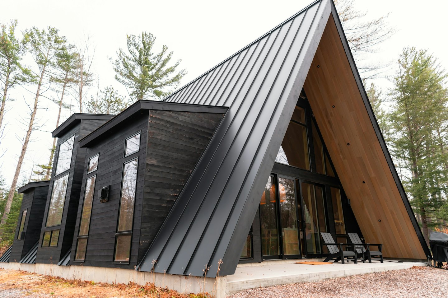 Nowoczesny dom w kształcie litery A z krzesłami Adirondack na patio.